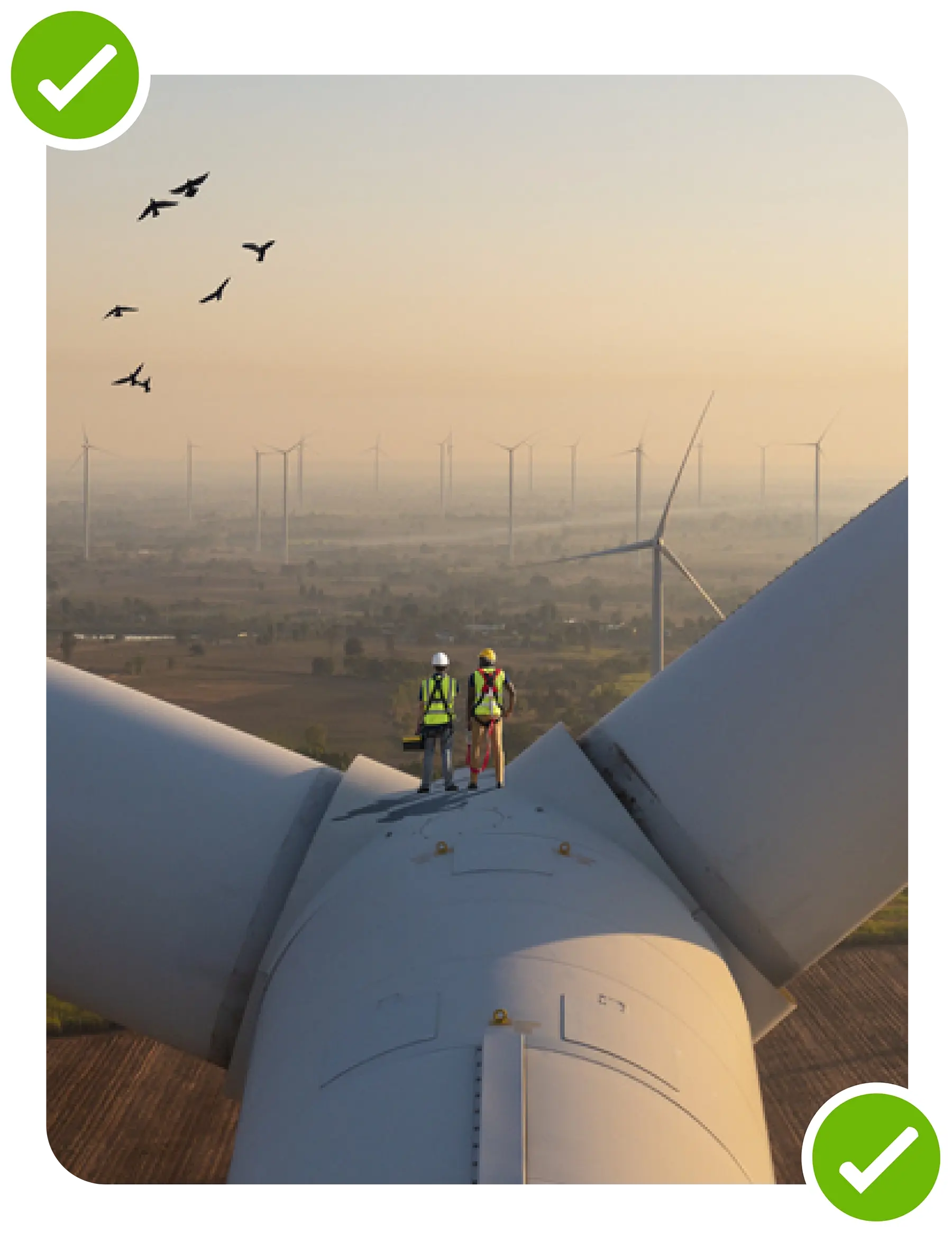 An image of two people standing on top of a wind turbine.